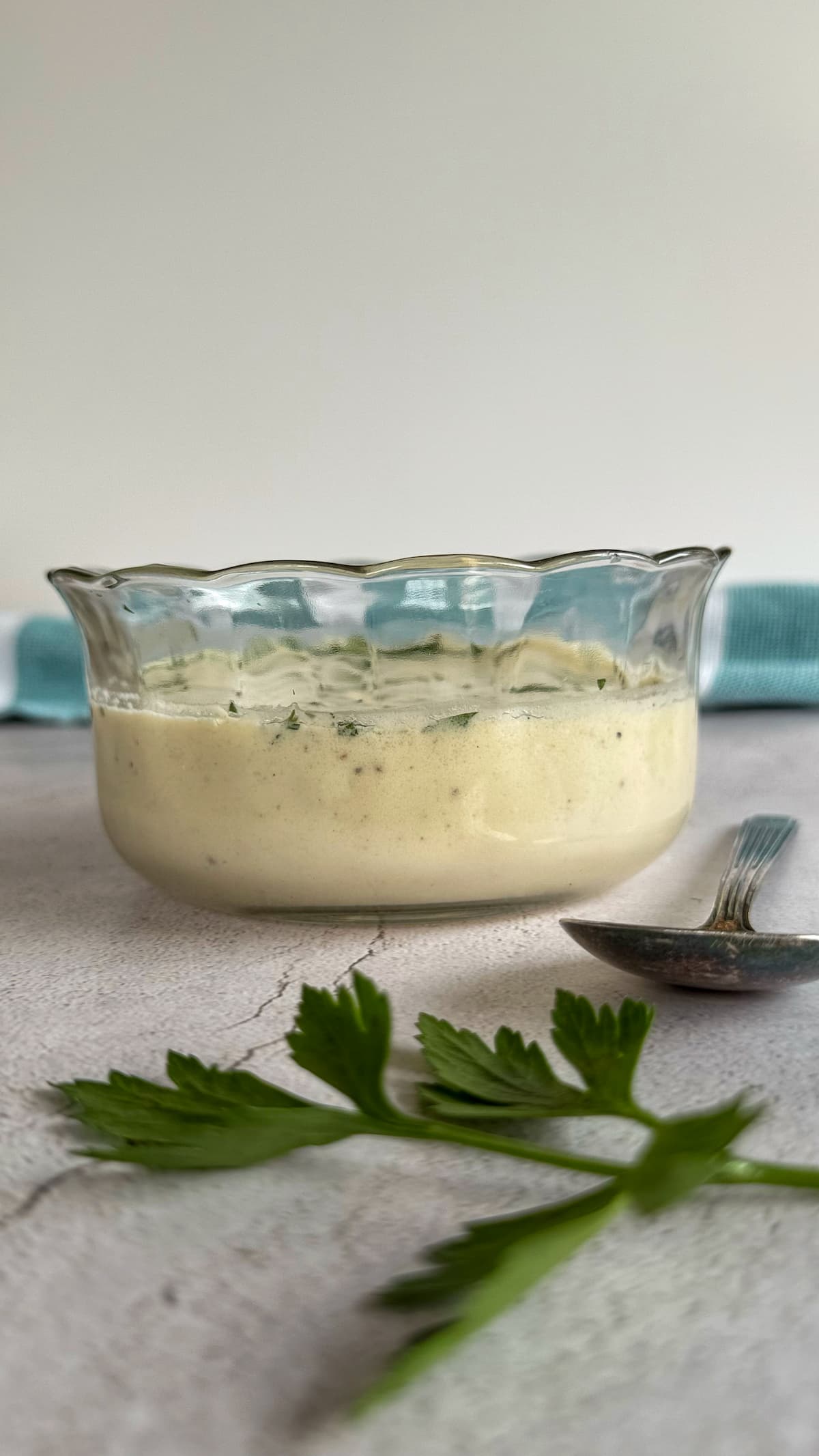 low carb alfredo sauce in a bowl next to a spoon and a sprig of fresh parsley.