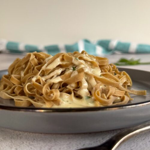 plate of creamy fettuccine alfredo, fork in front of the plate.