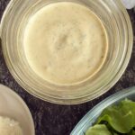 peppercorn ranch dressing in a jar next to a bowl of chopped romaine lettuce.