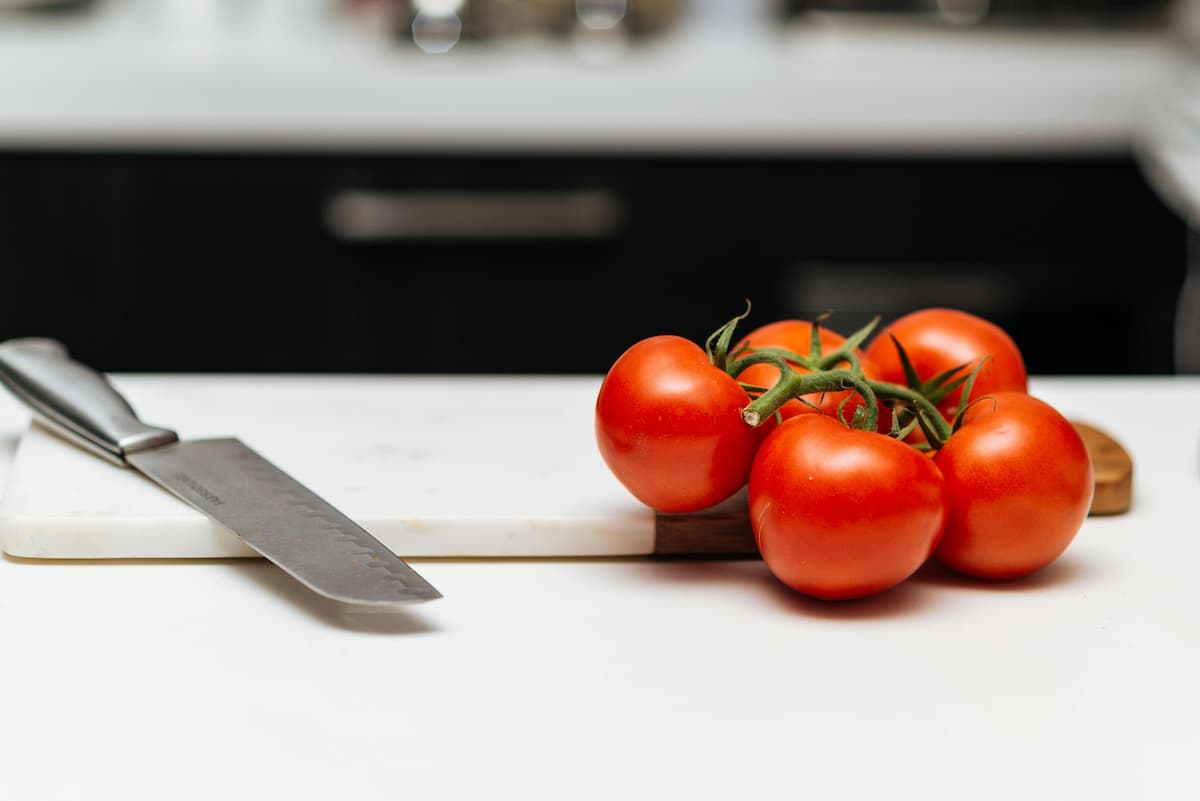 5 on the vine tomatoes on a cutting board next to a knife
