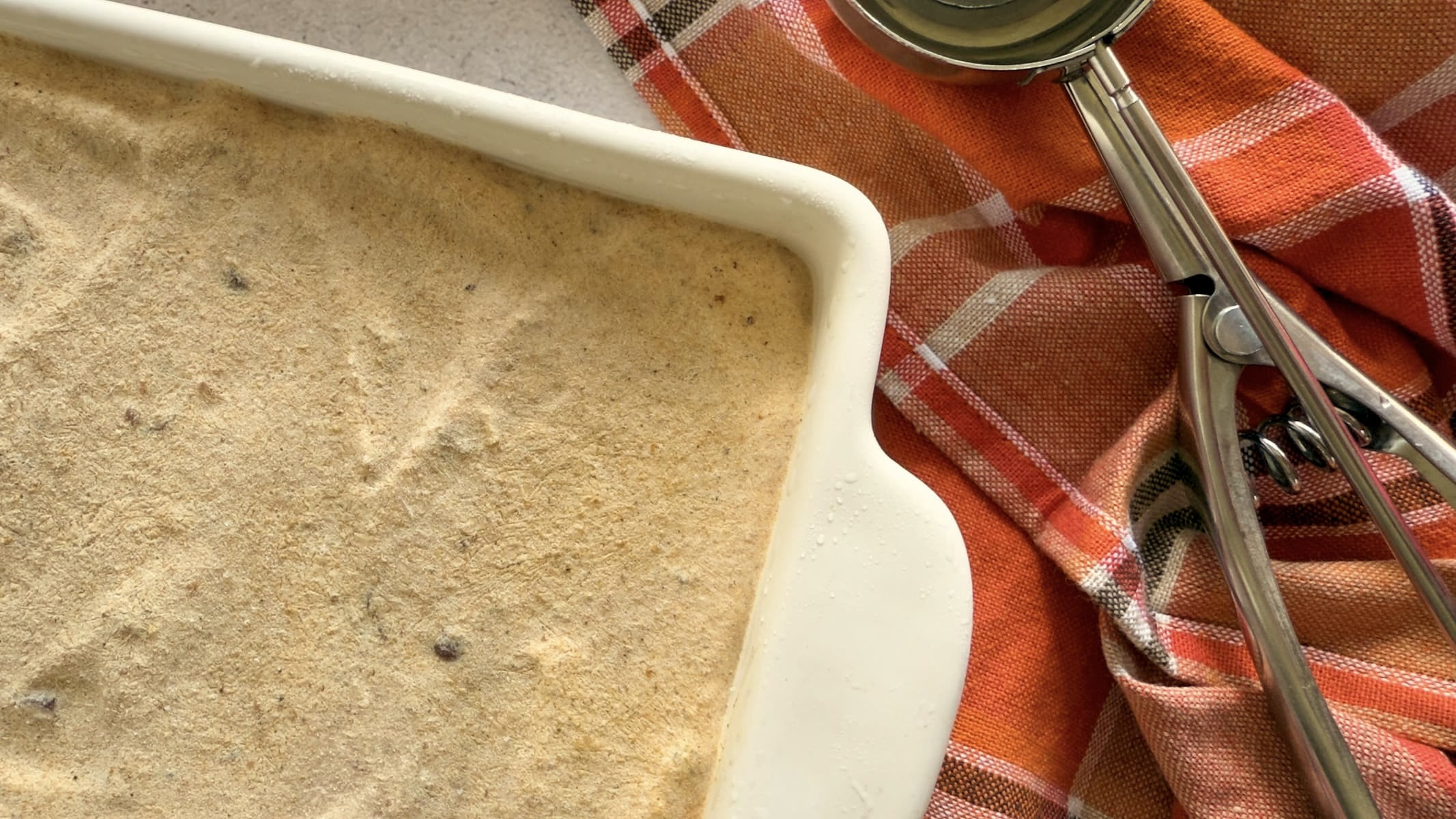 cut off photo of pumpkin spice ice cream next to an ice cream scoop.