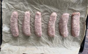 raw brats on a parchment lined baking sheet.