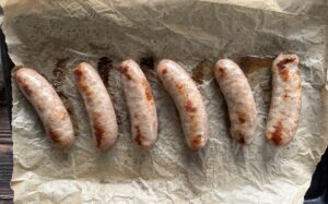 baked bratwurst sausage on a parchment lined baking sheet.