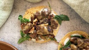 chopped steak tacos with creamy brie cheese, walnuts, arugula, and a creamy white sauce on small tortillas.