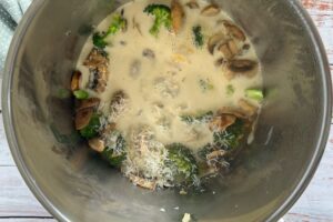 soup pot with broccoli florets, sliced mushrooms, and freshly grated parmesan cheese in a creamy broth.