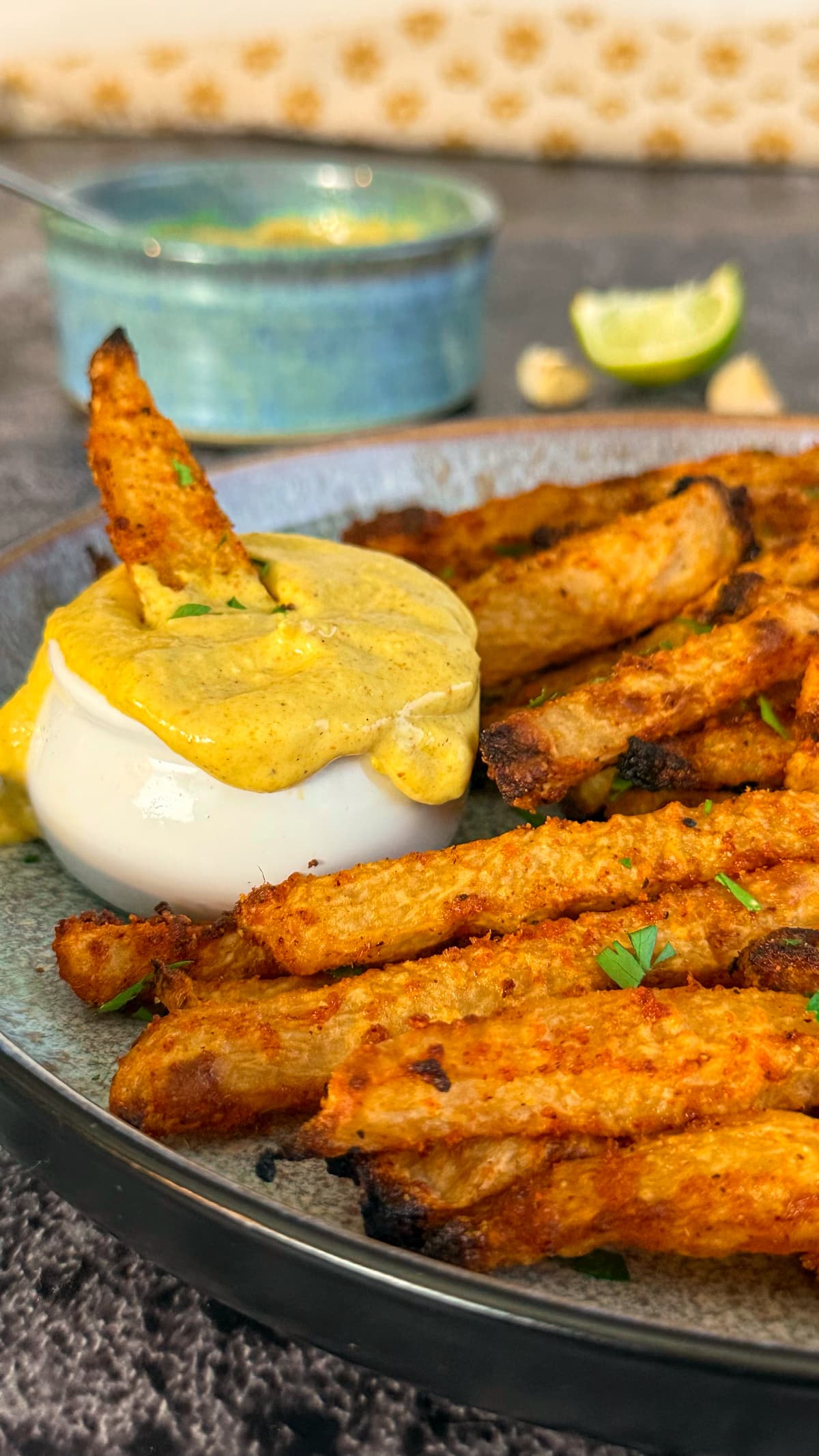 plate of fries with fresh chopped parsley, small ramekin of bright yellow curry mayonnaise, fry dipping into the mayo.