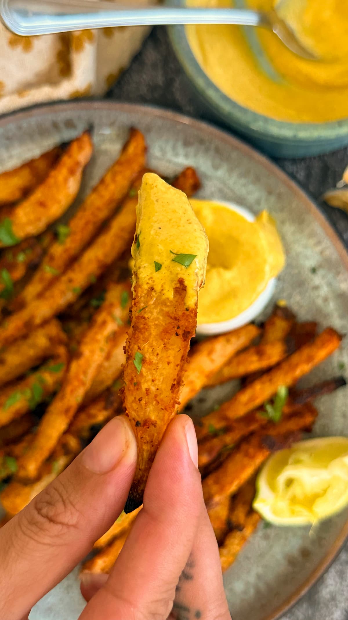 curry mayo on a fry over a plate with more.