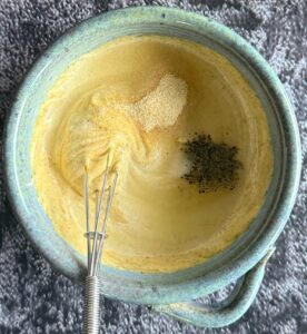 mayo in a bowl mixed with spices. small whisk in the bowl.