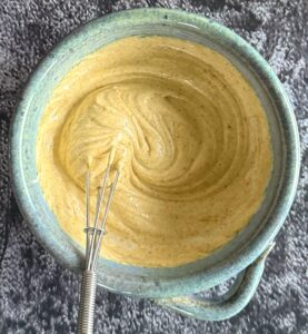 curry mayo in a blue bowl with a little whisk.