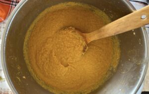 pot of orange soup with a wooden spoon.
