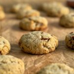 freshly baked pecan coconut cookies spread out on a piece of parchment paper.