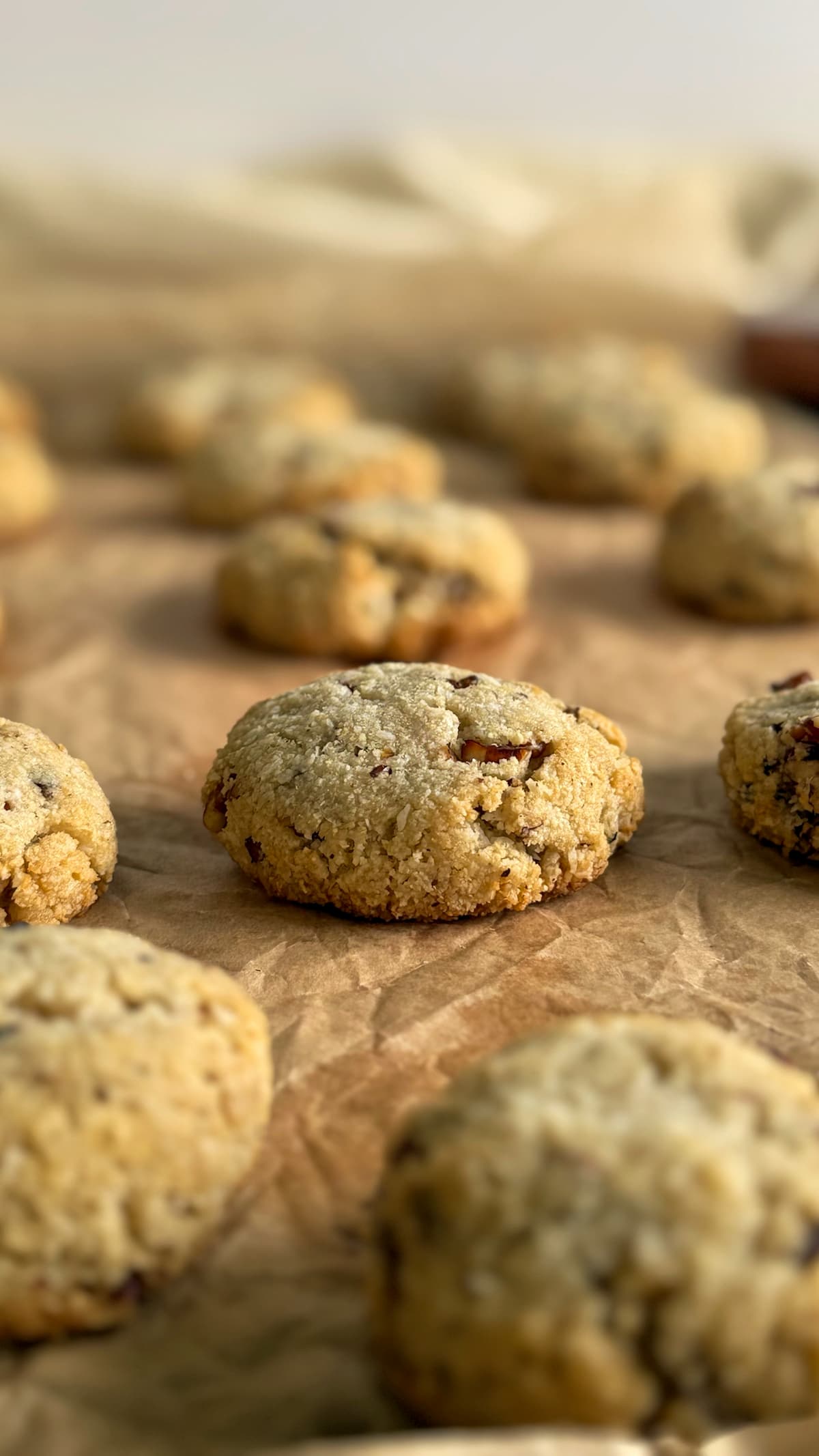 freshly baked pecan coconut cookies spread out on a piece of parchment paper.