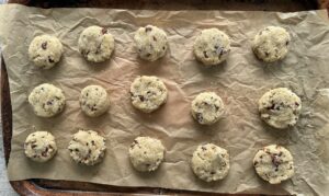 15 unbaked coconut pecan cookies on a parchment lined baking sheet.