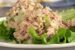 tuna salad with celery, shallots, and fresh dill stacked on leaf lettuce on a white plate. a few pieces of fresh dill in the front.