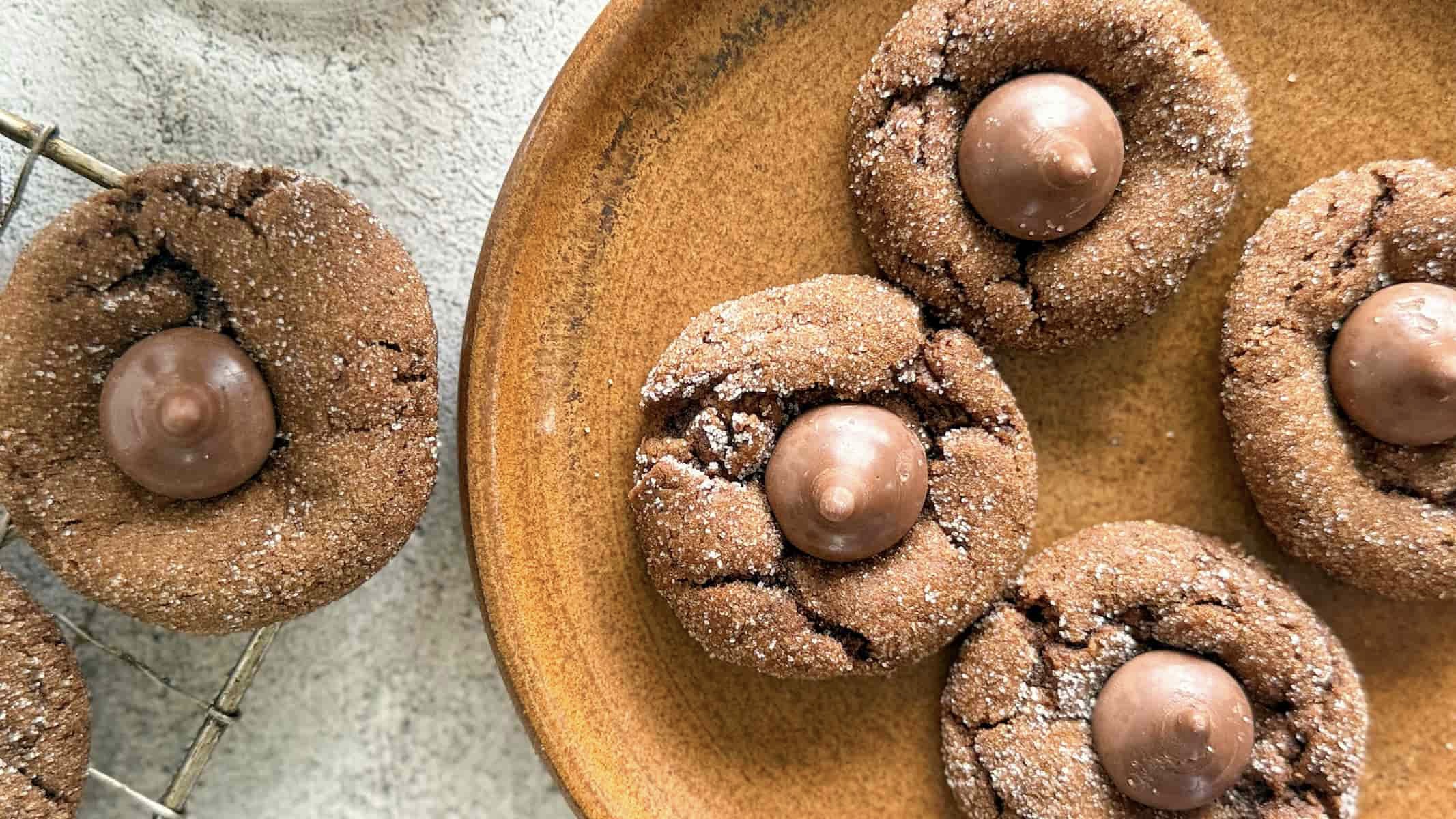 4 hershey kiss cookies on a plate next to 1 on a wire rack.