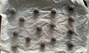 sugar coated brown cookie dough balls spread out on a parchment lined baking sheet.