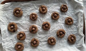 hershey kiss gingerbread cookies spread out on a parchment lined baking sheet.