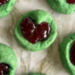 a few grinch thumbprint cookies with raspberry jam laid out.
