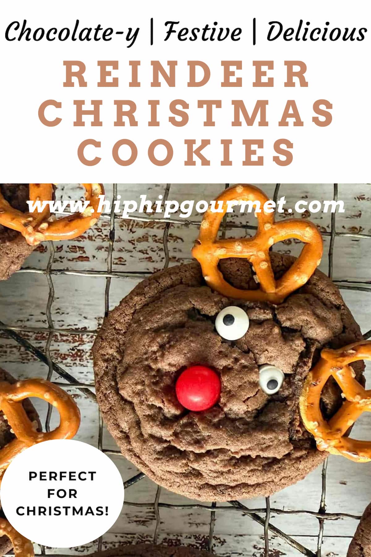 close up of reindeer christmas cookies with pretzel antlers, candy eyes, and a red candy nose on a wire rack.