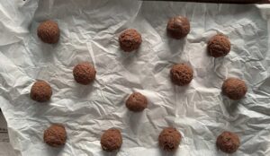 chocolate balls spread out on a parchment lined baking sheet.
