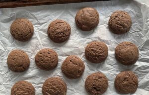 freshly baked puffy chocolate cookies on a parchment lined baking sheet.