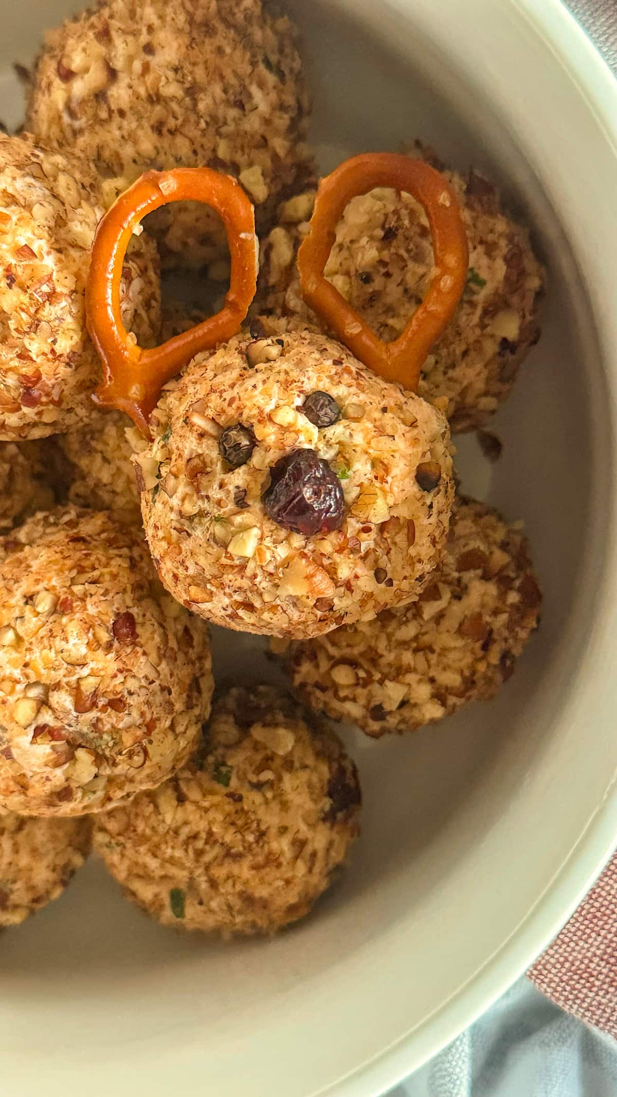 mini reindeer cheese ball in a white bowl on top of other mini cheese balls.