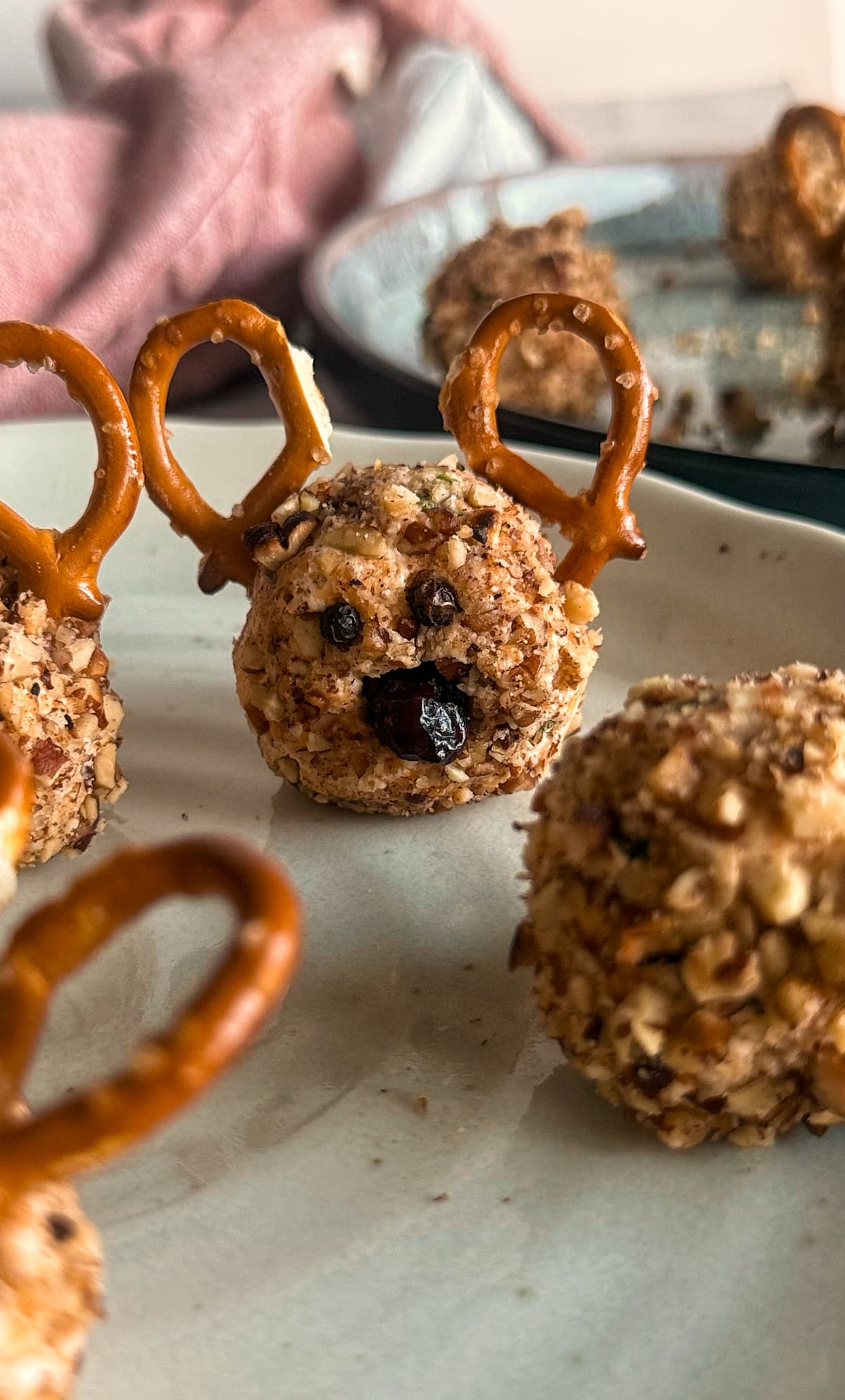 rudolph cheeseballs on a plate with dried cranberry noses and pretzel ears.