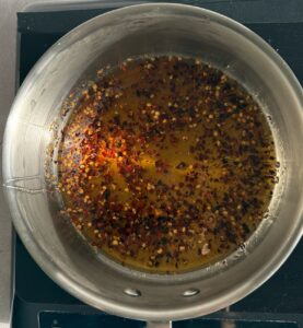 hot honey cooking in a silver pot on a burner.