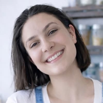 Woman smiling in front of a spice rack.