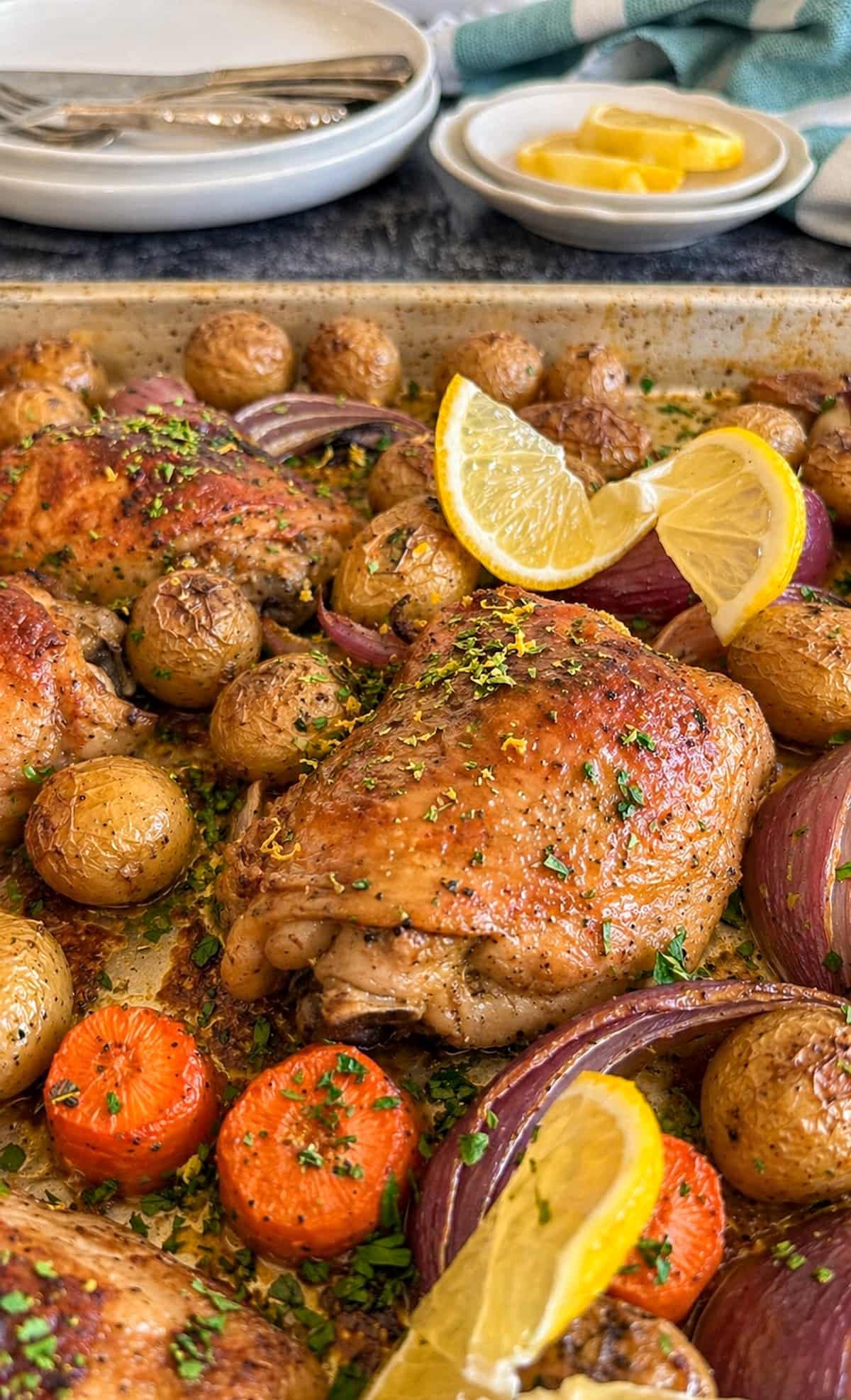 chicken and lemon tray bake with potatoes, red onions, and carrots.