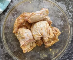 chicken thighs marinating in a brown sauce in a bowl.