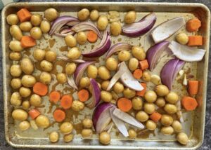 baby potatoes, carrot chunks, red onion wedges and smashed garlic cloves in a marinade spread out evenly on a large baking sheet.