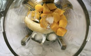 banana, ice cubes, and pieces of frozen mango in a blender.