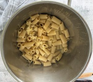 rigatoni in a pot with minced garlic.