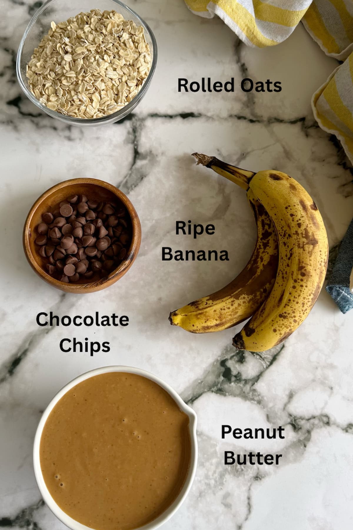 ingredients for 4 ingredient banana oatmeal cookies laid out - ripe bananas, rolled oats, chocolate chips, and peanut butter.