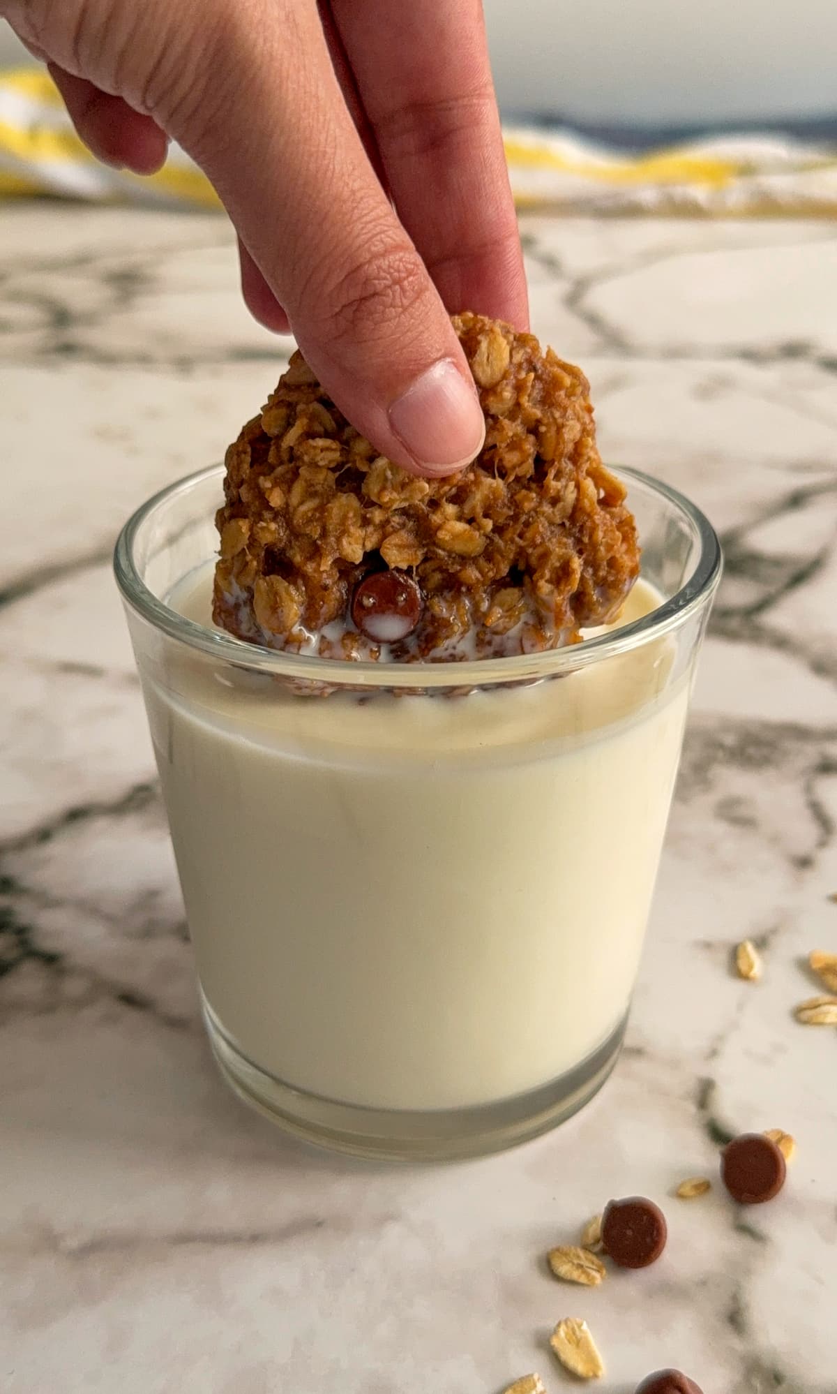 hand dipping an oatmeal cookie into a glass of milk.