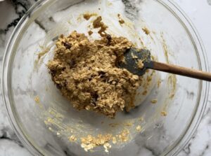 oat, chocolate chip, peanut butter, and banana mixture in a glass bowl with a small rubber spatula.
