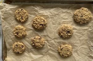 8 unbaked 4 ingredient banana oatmeal cookies on a parchment lined baking sheet.