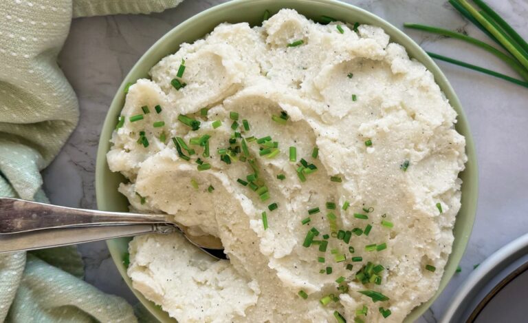 bowl of cottage cheese mashed potatoes topped with chives, two spoons in the bowl.