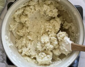 cottage cheese mashed potatoes in a pot with a rubber spatula.