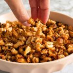 hand grabbing some crispy white beans out of a bowl.