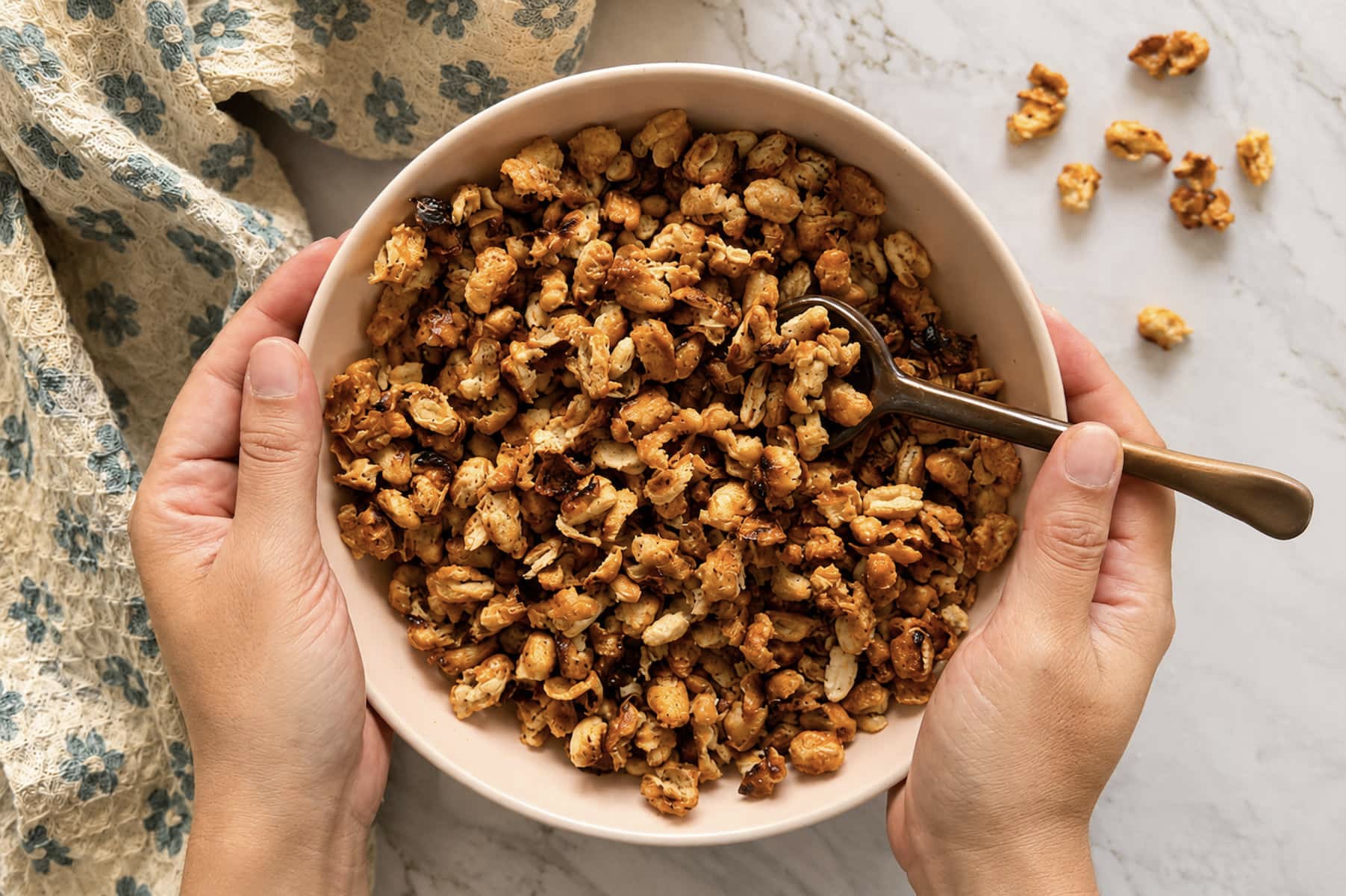 hands holding a bowl of crispy white beans with a spoon, some beans around on the outside.