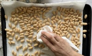 hand with a paper towel patting white beans down on a paper towel lined tray.