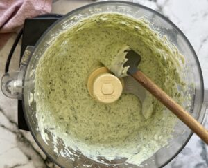 green goddess sauce in the base of a food processor with a rubber spatula.