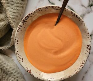 bright orange sauce in a bowl with a spoon.