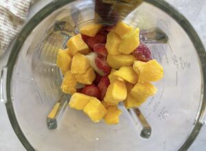 frozen mango chunks, strawberry pieces and banana in a blender.