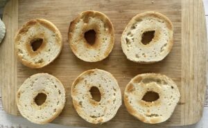 6 pieces of toasted bagel on a cutting board.