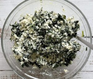 spinach and ricotta mixture in a glass bowl with a spoon.