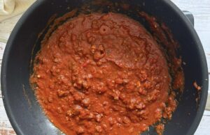 tomato meat sauce simmering in a black pot.