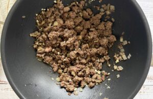 browned ground beef and minced garlic in a wok.